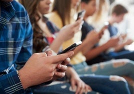 Un grupo de adolescentes mirando el móvil