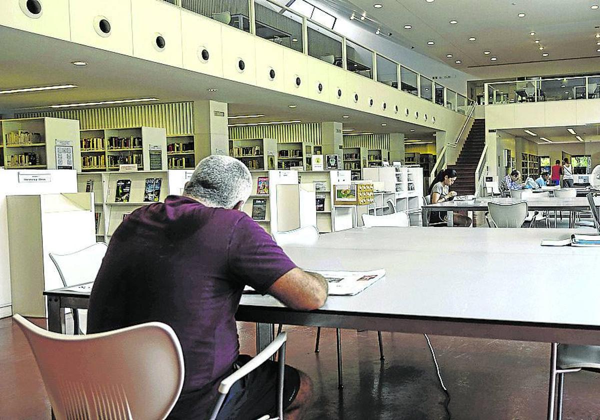 Un ciudadano lee un libro en una biblioteca pública en Sevilla.