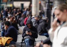 Un hombre consulta su teléfono móvil mientras una mujer habla a través del suyo.