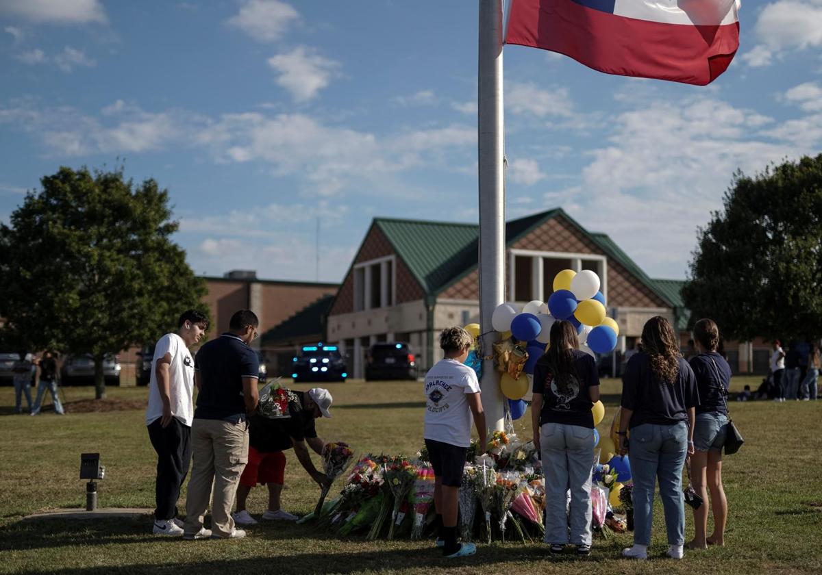 Varias personas colocan flores en un monumento improvisado en la escuela secundaria Apalachee de Winder, en Georgia, el día después de que un tiroteo que dejó cuatro muertos.