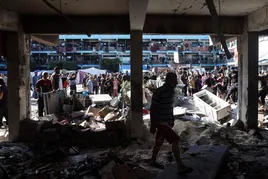 Palestinos inspeccionan el terreno de una escuela de Nuseirat después de que un ataque aéreo israelí impactara en el edificio.