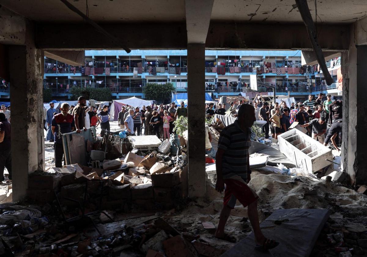 Palestinos inspeccionan el terreno de una escuela de Nuseirat después de que un ataque aéreo israelí impactara en el edificio.