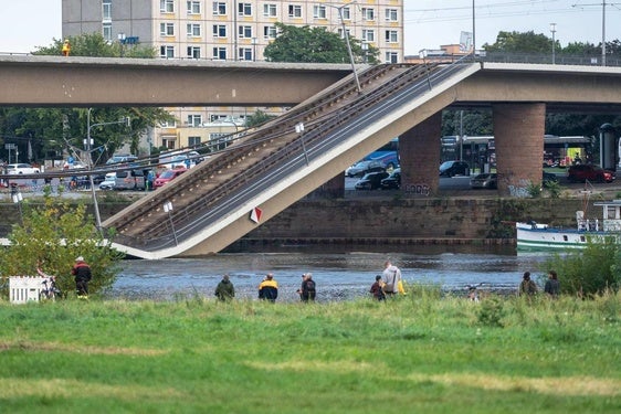 Un grupo de ciudadanos observa el tramo desplomado del puente de Carola desde la orilla del río Elba.