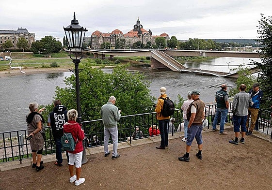 Viandantes observan el puente Carola parcialmente derrumbado sobre el río Elba, en el centro de la ciudad de Dresde.