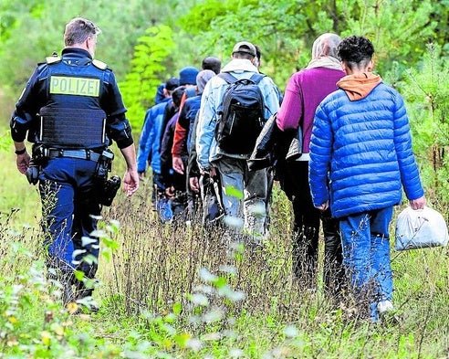 Un agente de la Policía alemana escolta a un gruipo de migrantes cerca de la frontera con Polonia.