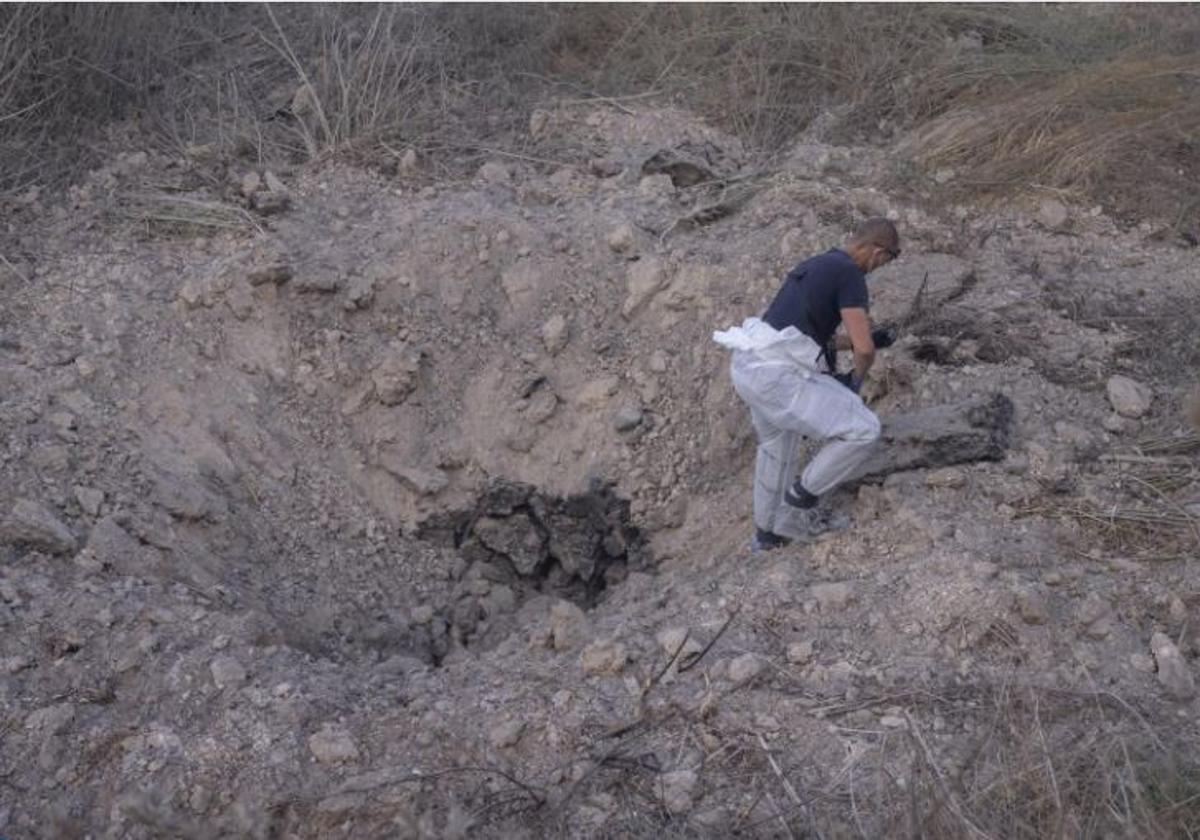 Una experta en explosivos busca restos del misil en el cráter dejado por la explosión.