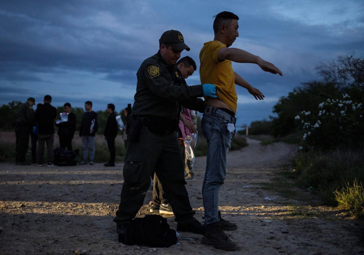 Agentes fronterizos de Estados Unidos cachean a un inmigrante ilegal chino tras cruzar la frontera con México.