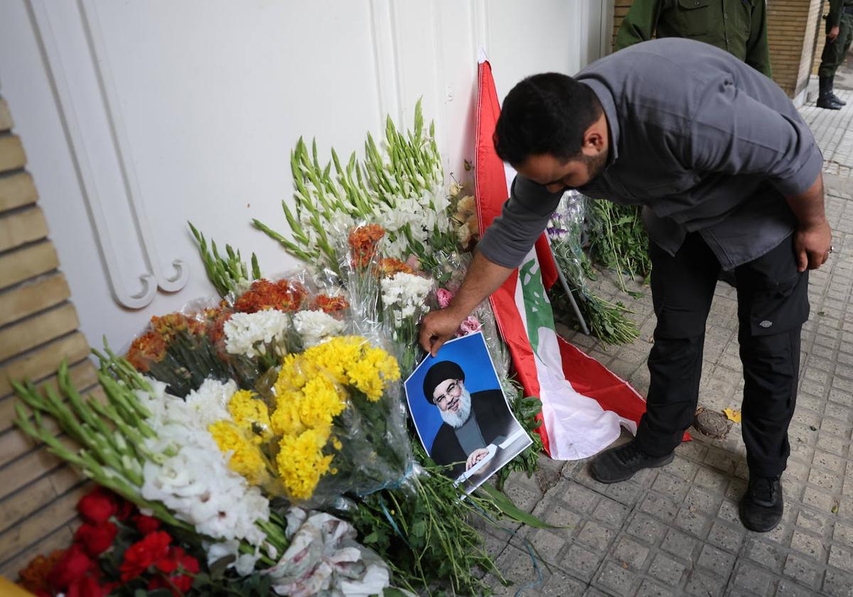 Un hombre coloca flores junto a un retrato de Hasán Nasrala.