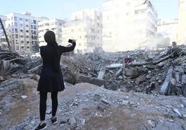 Una mujer toma una fotografía de un edificio destruido en el barrio de Haret Hreik.