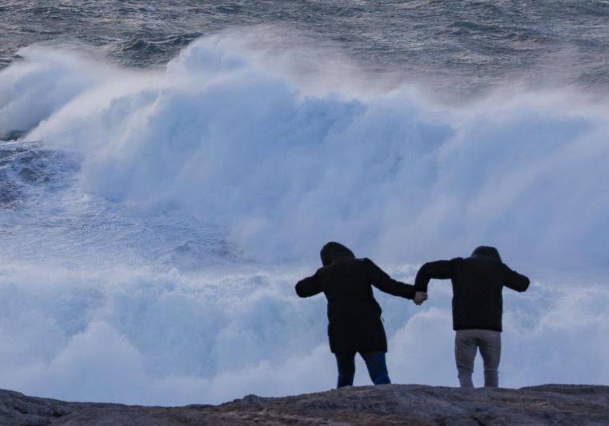 Dos personas frente a un temporal marítimo en el litoral gallego.