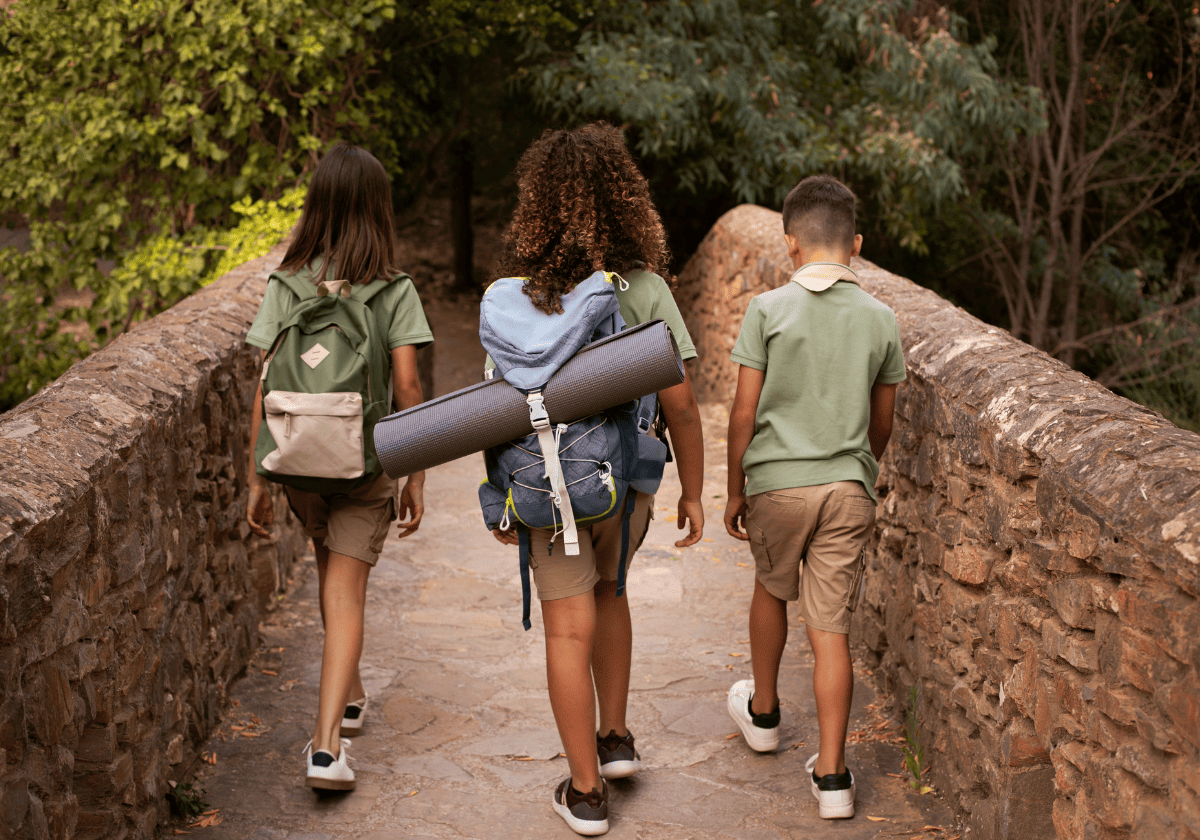 Niños caminando por un puente con material de excursión.