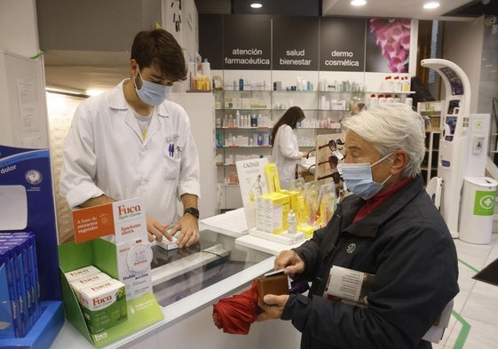 Los trabajadores de una farmacia y un cliente, con mascarillas.