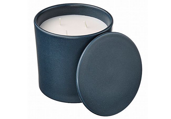 Vela decorativa blanca en recipiente azul oscuro con tapa.