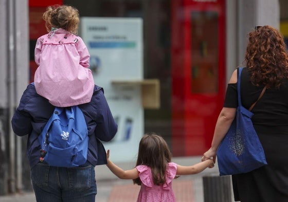 Unos padres acompañan a sus hijas al colegio.