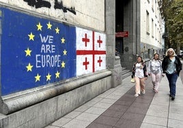 Un grupo de personas camina por una calle de Tiflis, la capital georgiana, en la que se exhibe un mural en favor de la adhesión a la UE.