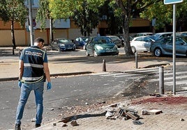 Un agente inspecciona el lugar del tiroteo registrado en el Polígono Sur de Sevilla.