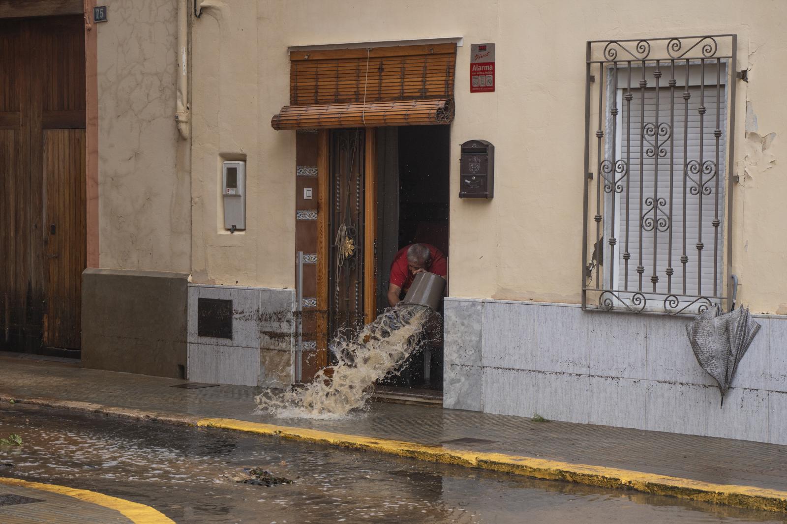 Un hombre achica agua de su casa en Llombai, Valencia.