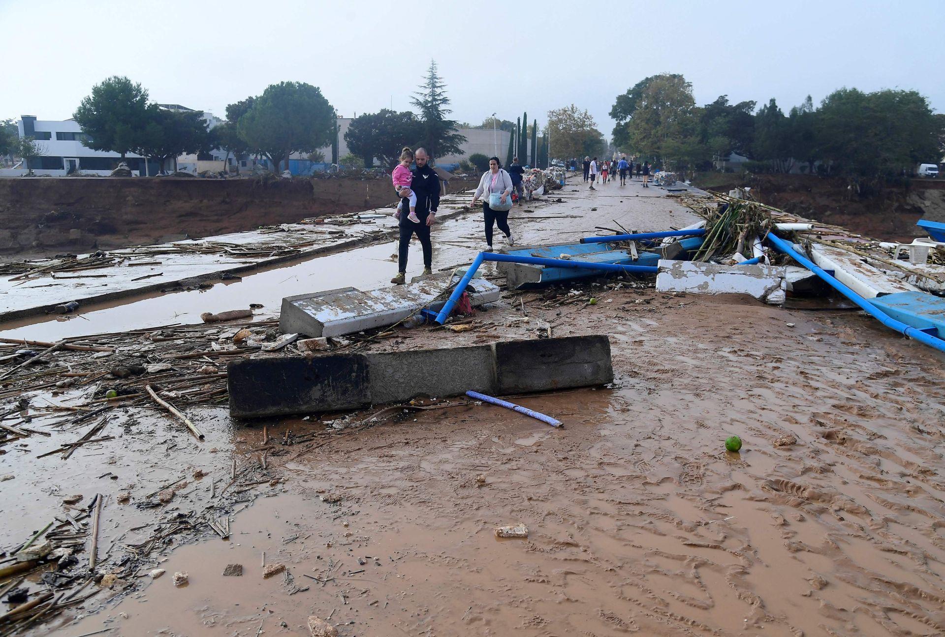 Una familia camina por una calle cubierta de barro tras las inundaciones en Picuana, cerca de Valencia