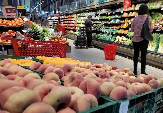 Personas comprando fruta en un supermercado.