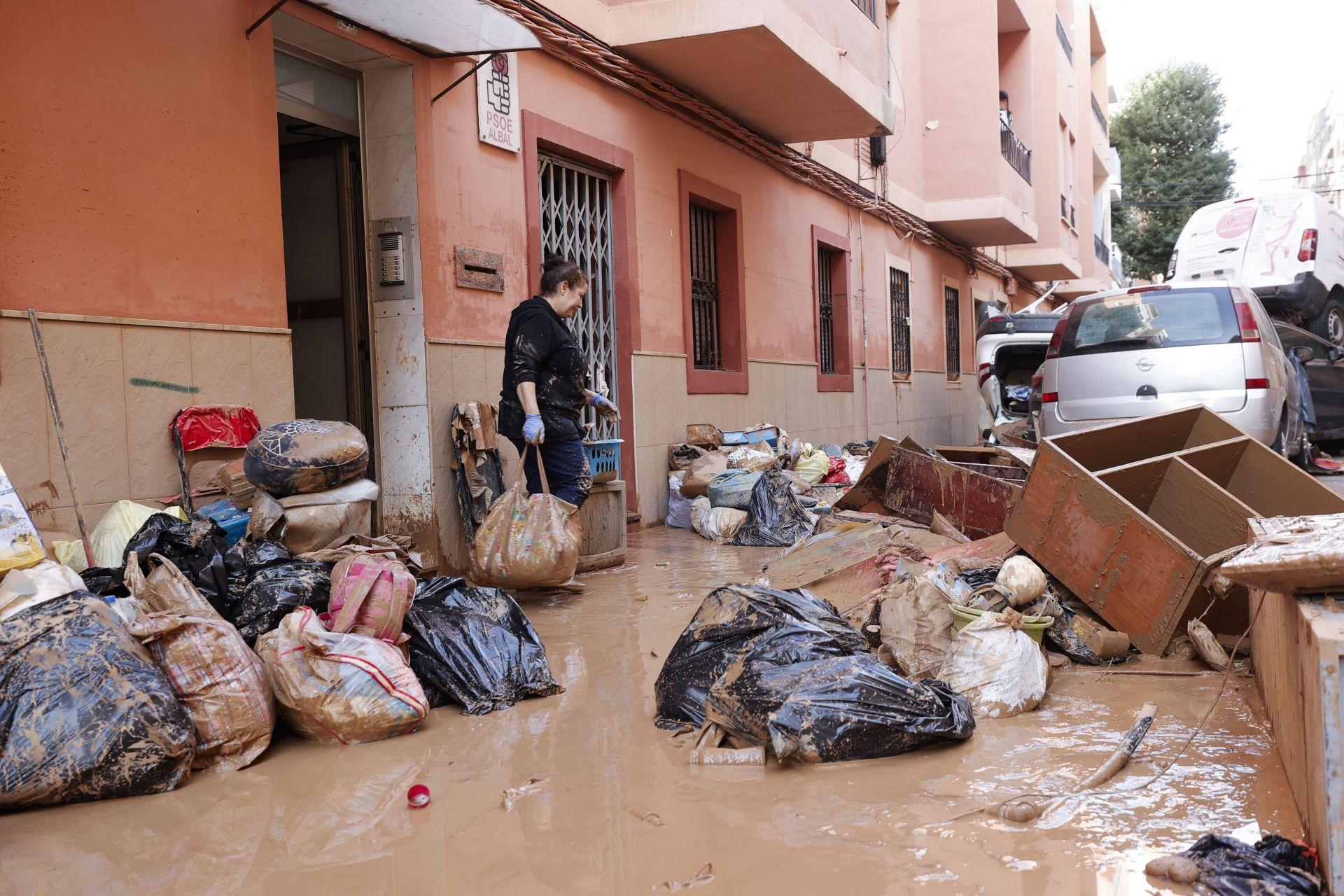 Una mujer saca de su vivienda sus pertenecias tras las intensas lluvias caídas por la fuerte DANA, este jueves en Catarroja, Valencia