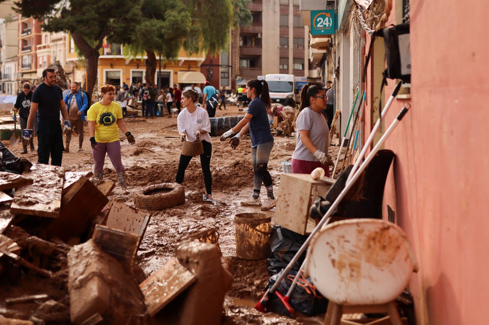 Voluntarios ayudan a retirar el lodo en una calle de Paiporta, Valencia