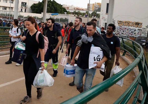 Personas se dirigen con víveres y productos de primera necesidad hacia La Torre desde la pasarela que comienza en San Marcelino