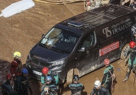 Un furgón de la funeraria sale de un garaje con cadáveres localizados tras el paso de la DANA en el barrio de la Torre, en Valencia.