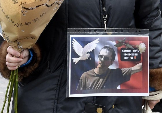 Una mujer sostiene un ramo de flores y una fotografía recordando a Samuel Paty, el 18 de octubre de 2020.