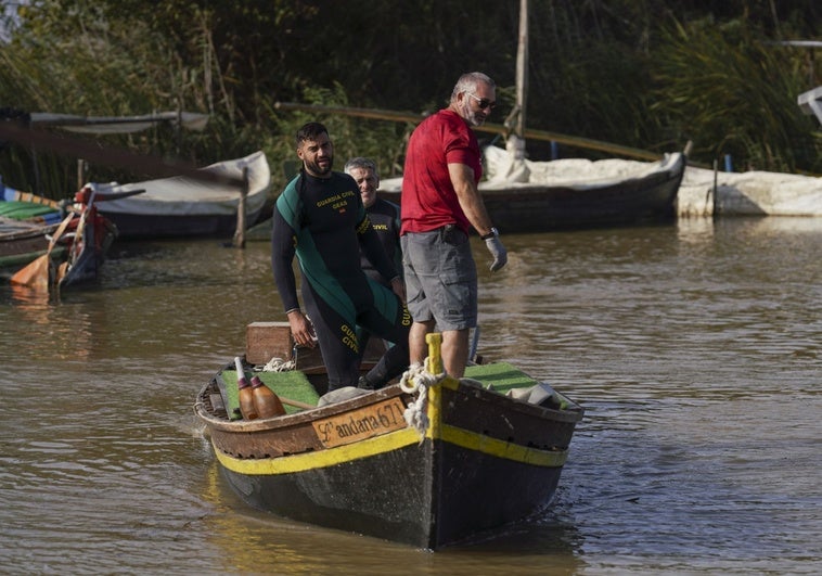 Dos buceadores de los GEAS en una las embarcaciones de un pescador de La Albufera.