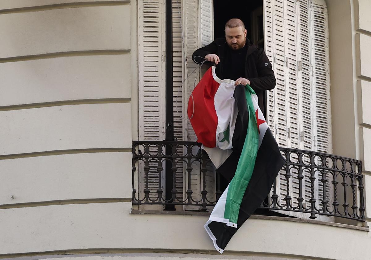 Una persona coloca la bandera insurgente en la embajada de Siria en Madrid.