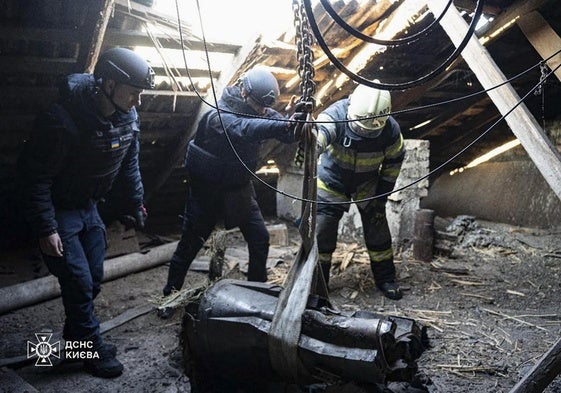 Un equipo de rescate retira los restos de un cohete ruso que perforaron el tejado de una casa.