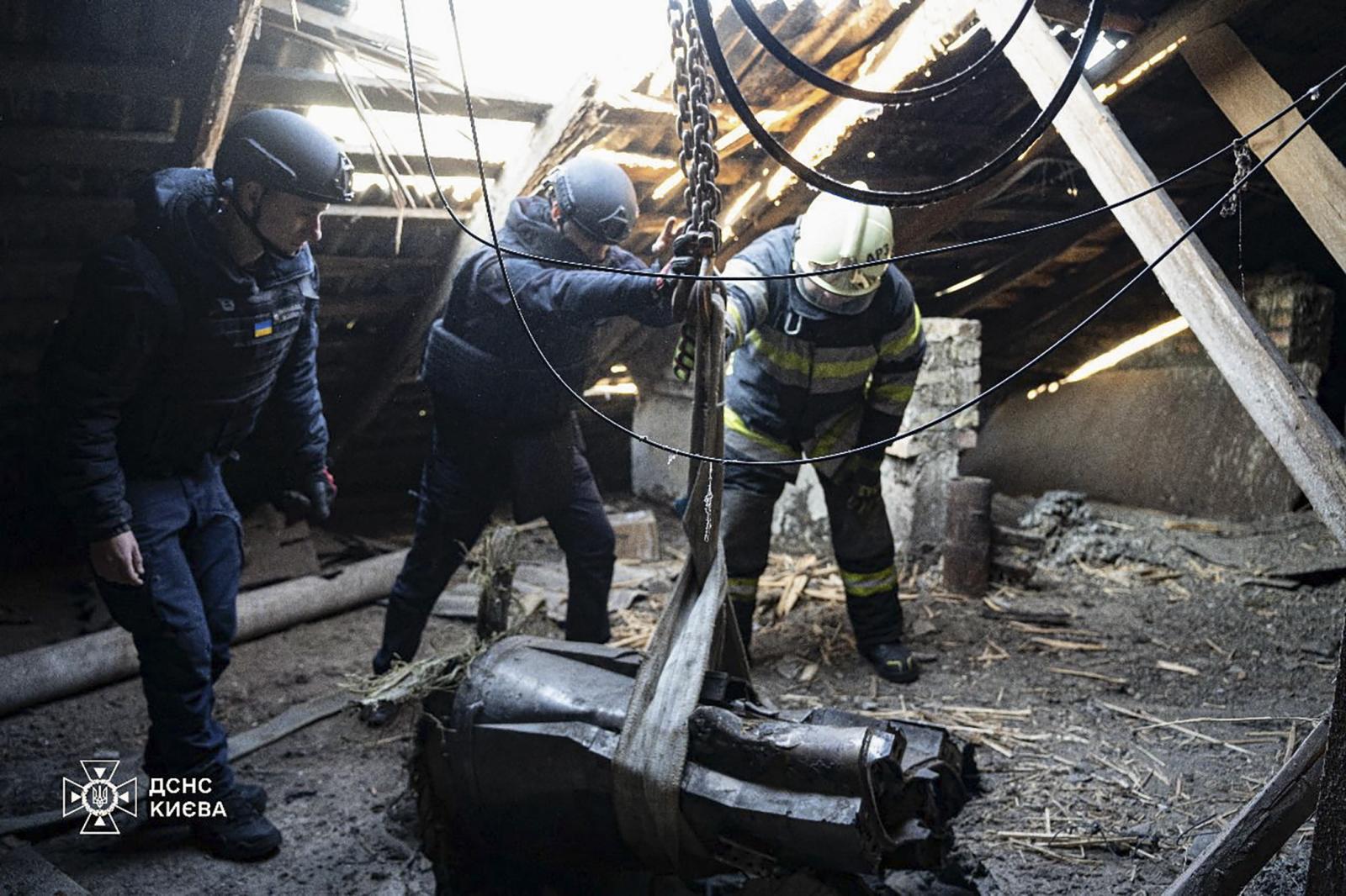 Un equipo de rescate retira los restos de un cohete ruso que perforaron el tejado de una casa.