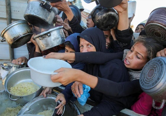 Palestinos aguardan a recibir comida en un punto de reparto en el sur de Gaza.