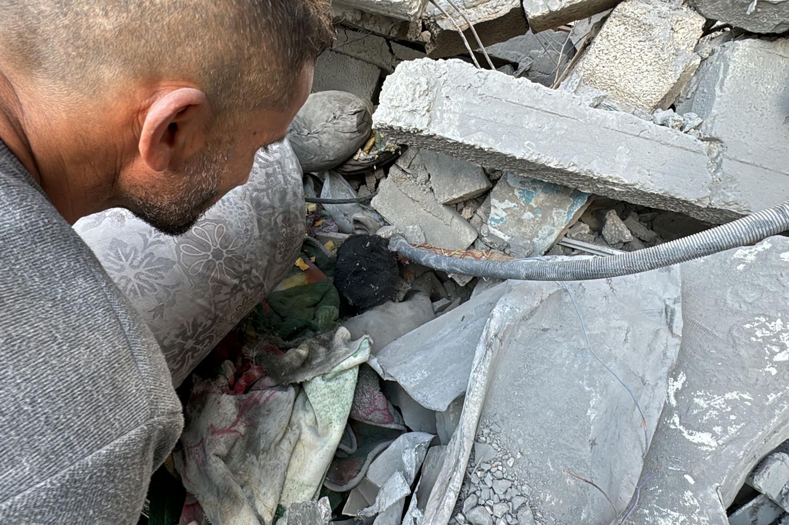 Un hombre palestino observa un cuerpo atrapado bajo los escombros de un edificio atacado por Israel en el norte de Gaza.