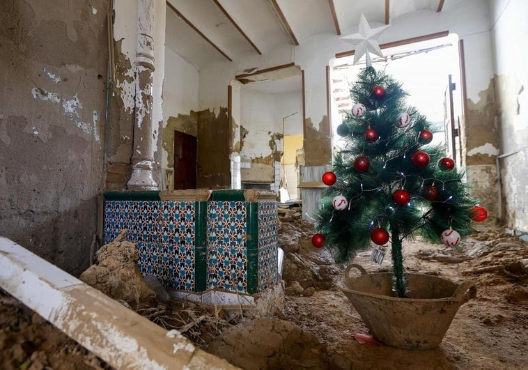 Un árbol de Navidad decora una planta baja repleta de escombro y lodo en una cas de Paiporta (Valencia).