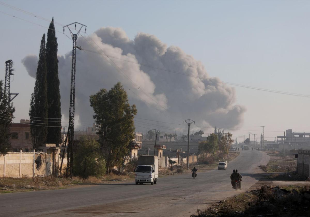 Unos combatientes entran en motocicletas en el distrito de Rashidin, en las afueras de Alepo, con el humo de una explosión de fondo.