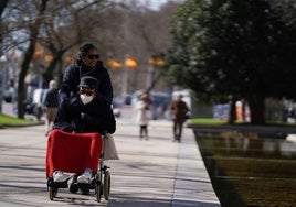 Una cuidadora saca a pasear a un hombre en silla de ruedas.