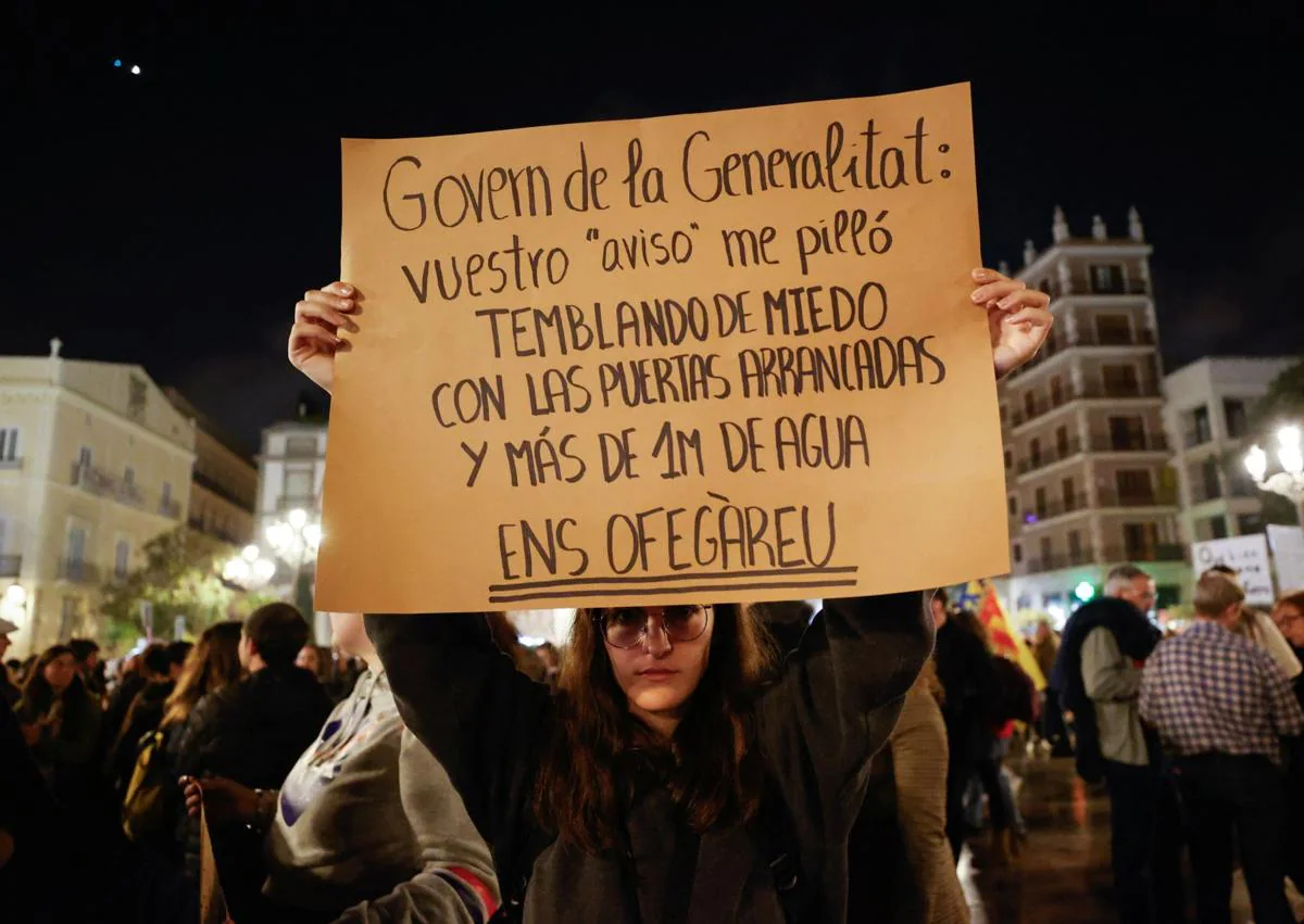 Imagen secundaria 1 - En la imagen superior, varios manifestantes lanzan barro antes las puertas de un edificio oficial, debajo una pancarta criticando la tardanza en los avisos de la Generalitat por la DANA y, por última, una mujer no puede resistir emocionarse durante la protesta.