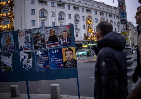 Un hombre pasa junto a un cartel electoral en una calle de Bucarest, la capital rumana.