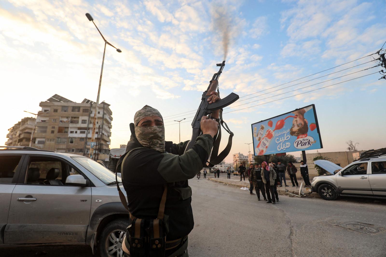 Un combatiente sirio antigubernamental dispara su rifle al aire en las calles de la ciudad de Hama.