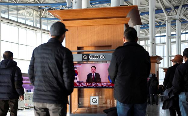Surcoreanos siguen el discurso del presidente en una estación de tren de Seúl.