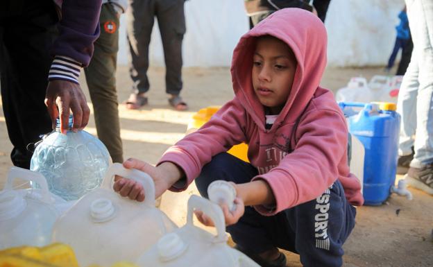 Un niño palestino recoge dos garrafas de agua en Khan Younis.