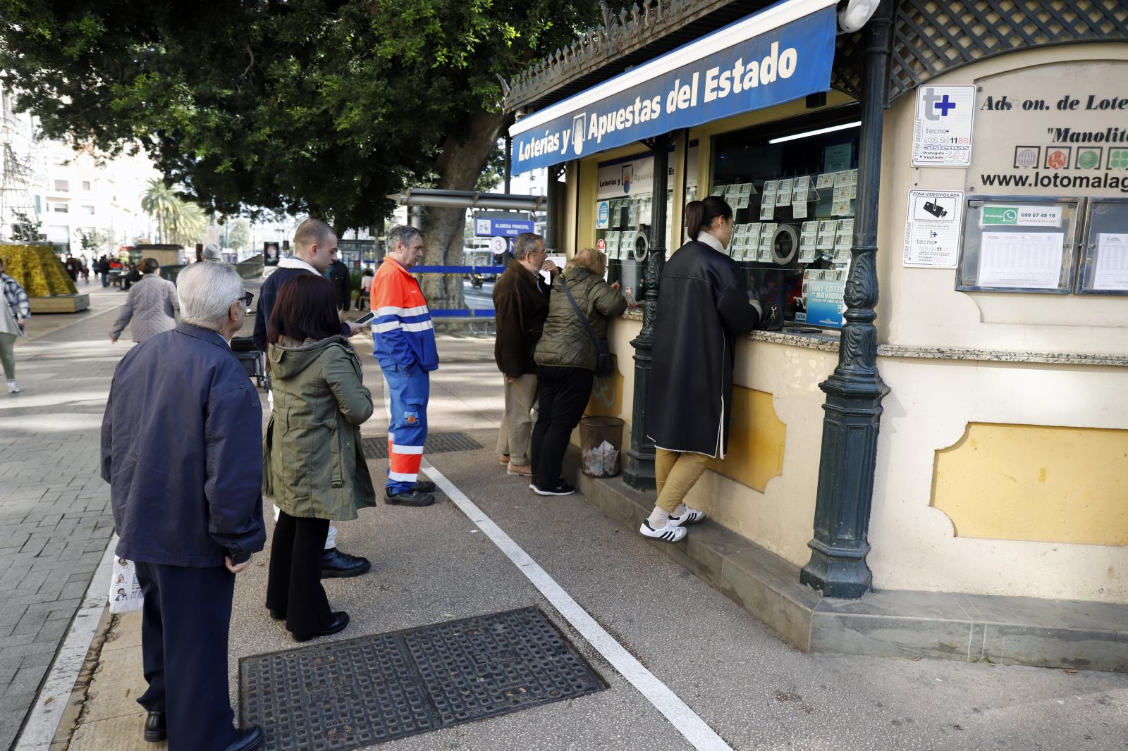 Varias personas hacen cola para comprar décimos de la Lotería de Navidad