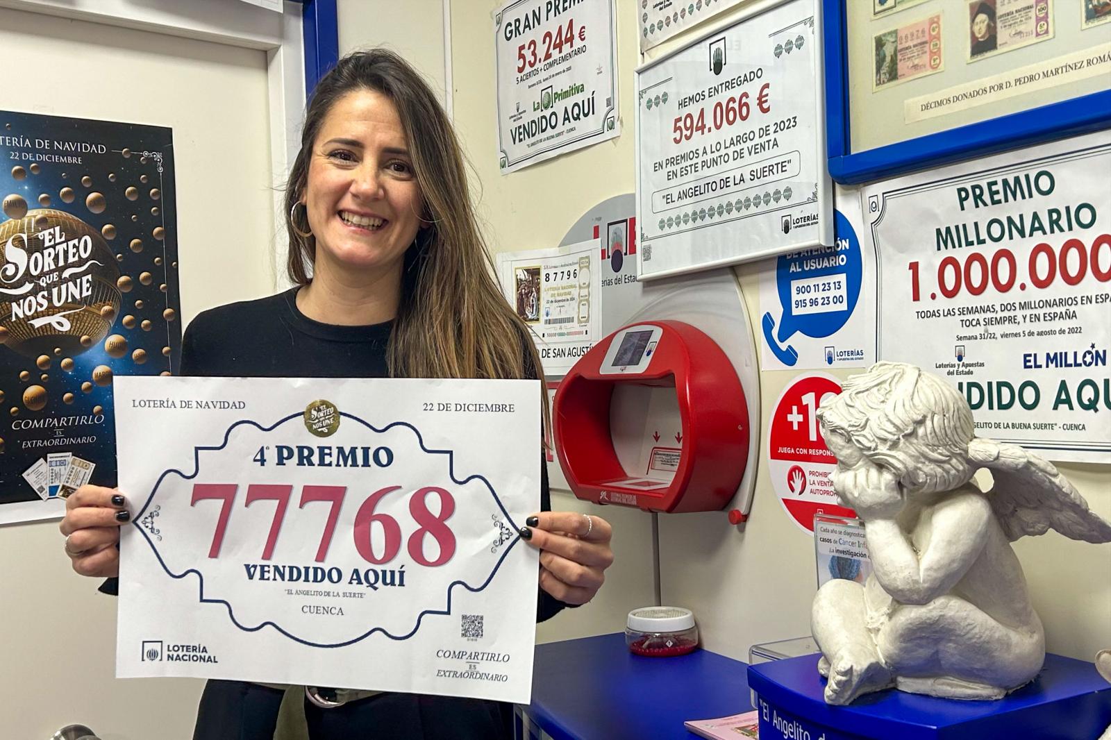 Clara Cañizares, lotera de la administración El Angelito de la Suerte de Cuenca, muestra el número 77768, premiado con un cuarto premio