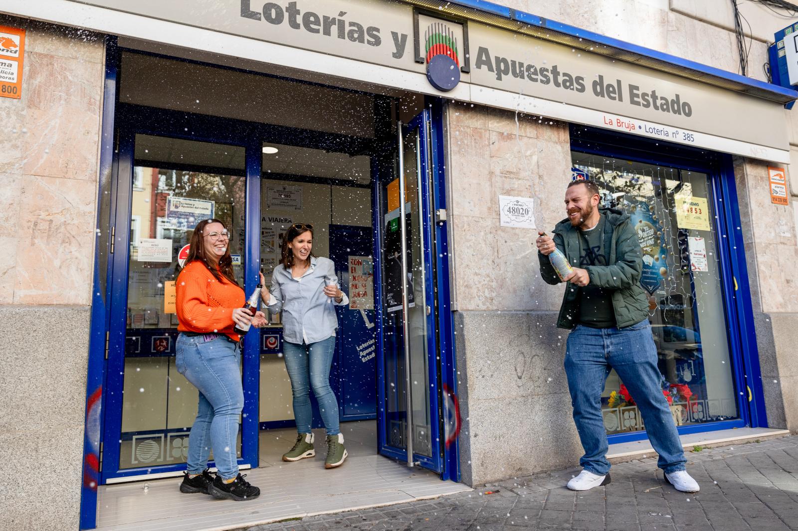 Tres personas celebran en Madrid uno de los cuartos premios con una botella de champán