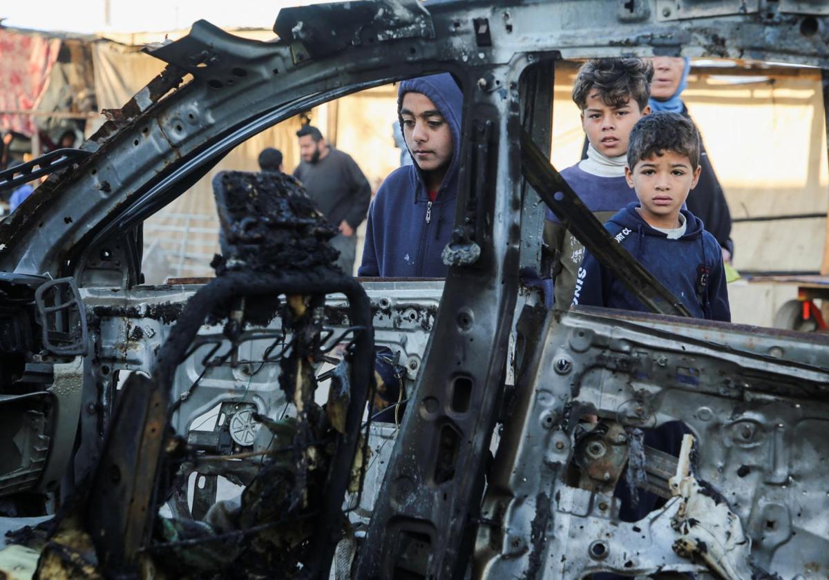 Niños palestinos miran un coche calcinado.