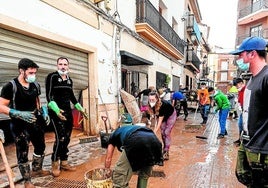 Varios vecinos de Chiva quitan barro y lodo.