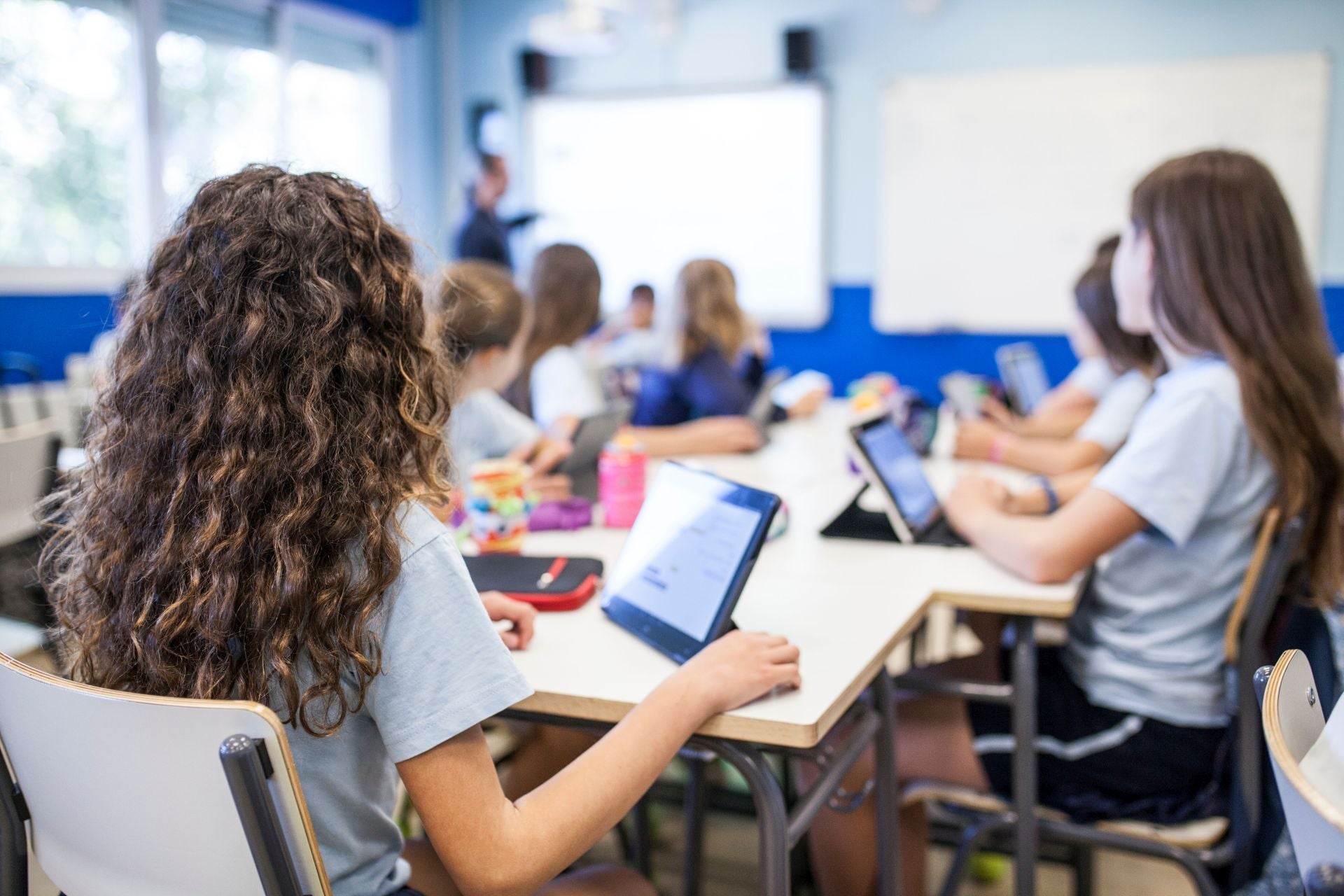 Un grupo de alumnos atiende a su profesora con una tableta.