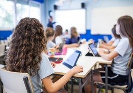 Un grupo de alumnos atiende a su profesora con una tableta.