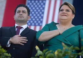 Jenniffer González, la nueva gobernadora de Puerto Rico, escucha el himno de Estados Unidos durante la ceremonia de toma de posesión junto a su marido, José Yovin Vargas.